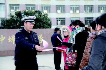 淄博2.6萬名學生盼有幼兒園校車及中小學校車坐(圖) 交警在學校門口向家長發放校車安全宣傳單(資料片)。